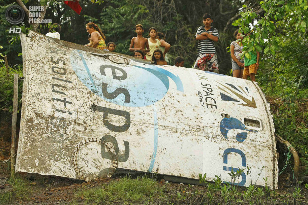 Local residents stand around what local media is calling a piece of an Ariane space rocket near Salinopolis